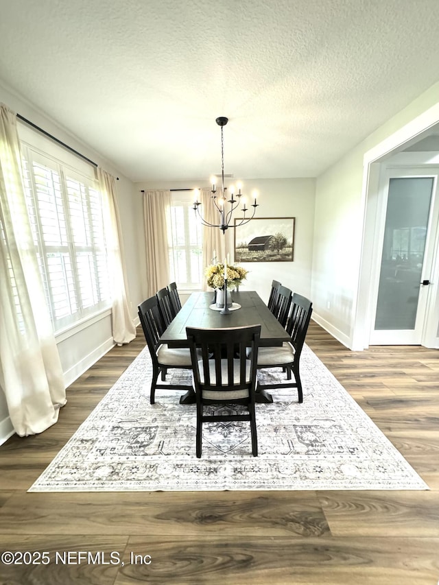dining space featuring a chandelier, baseboards, a textured ceiling, and dark wood-style floors
