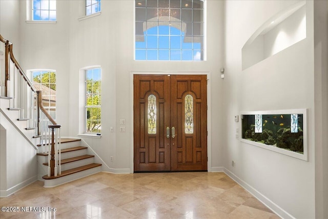 entryway featuring stairway, baseboards, and a towering ceiling