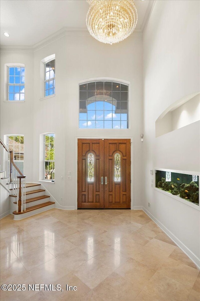 entrance foyer with stairs, baseboards, a notable chandelier, and crown molding