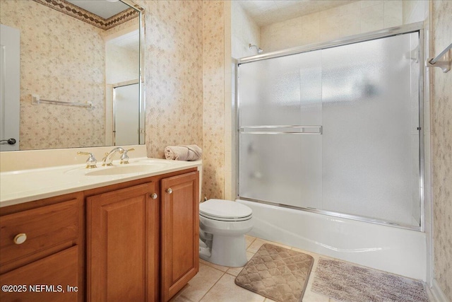 full bath featuring wallpapered walls, toilet, shower / bath combination with glass door, tile patterned floors, and vanity