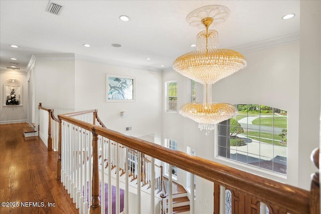 hall with crown molding, a notable chandelier, an upstairs landing, and visible vents
