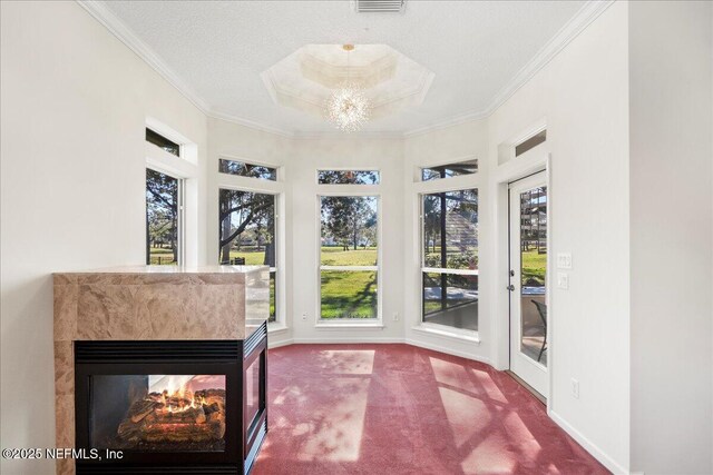 sunroom with visible vents, a raised ceiling, ornamental molding, carpet flooring, and baseboards