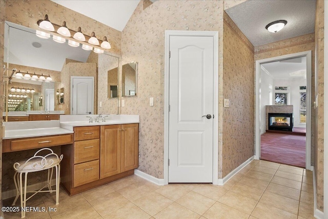 full bathroom with baseboards, wallpapered walls, lofted ceiling, a multi sided fireplace, and tile patterned floors