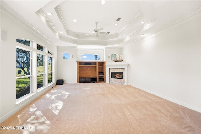 unfurnished living room featuring baseboards, visible vents, a tray ceiling, ceiling fan, and light colored carpet