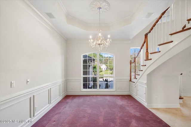 interior space featuring crown molding, carpet, stairway, a notable chandelier, and a raised ceiling