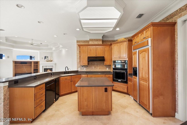 kitchen featuring under cabinet range hood, a peninsula, black appliances, and dark countertops