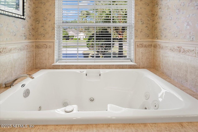 bathroom featuring wallpapered walls, a tub with jets, and a wainscoted wall