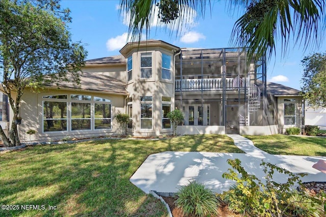 rear view of property featuring stucco siding, a lawn, a balcony, and glass enclosure