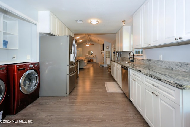 kitchen with washing machine and dryer, a ceiling fan, appliances with stainless steel finishes, a sink, and wood finished floors