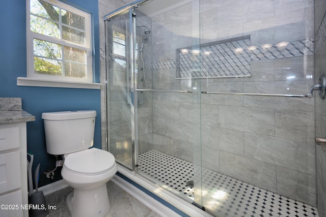 bathroom with toilet, a shower stall, vanity, and baseboards