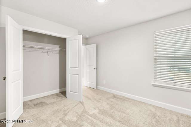 unfurnished bedroom featuring a closet, baseboards, and carpet flooring