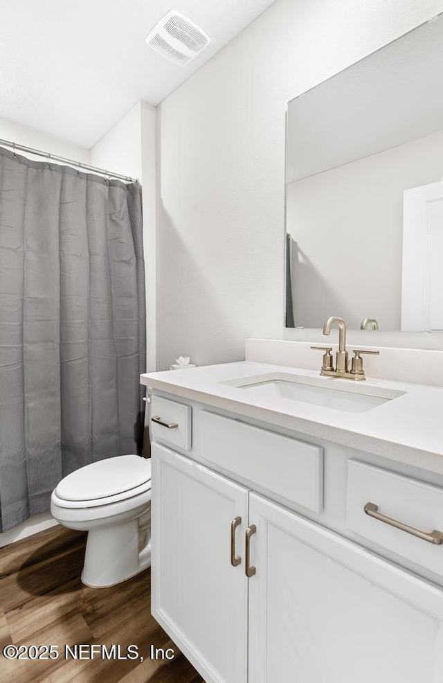 full bathroom featuring vanity, wood finished floors, visible vents, curtained shower, and toilet