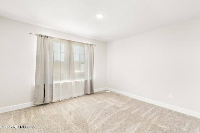 carpeted spare room featuring baseboards