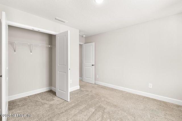 unfurnished bedroom with a closet, visible vents, baseboards, and carpet