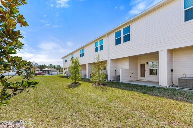 rear view of property featuring central AC unit, a lawn, and a patio area