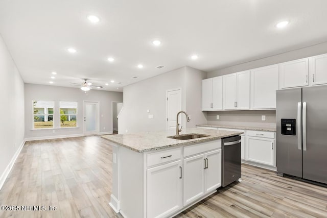 kitchen with a sink, white cabinetry, appliances with stainless steel finishes, light wood finished floors, and ceiling fan