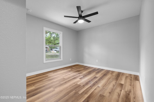spare room with baseboards, wood finished floors, and a ceiling fan