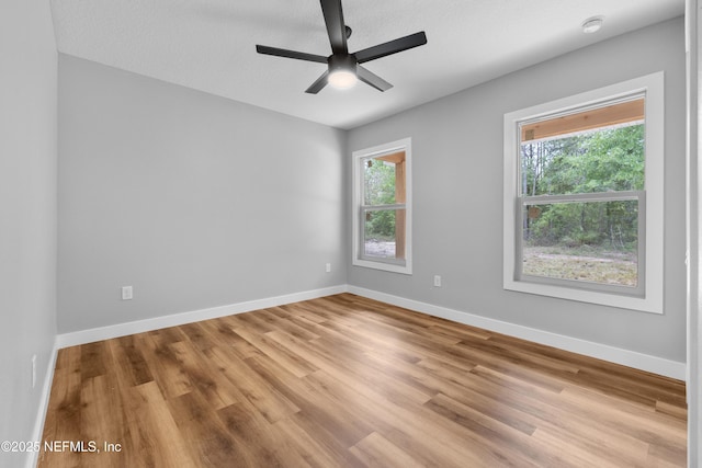 unfurnished room with a ceiling fan, light wood finished floors, and baseboards