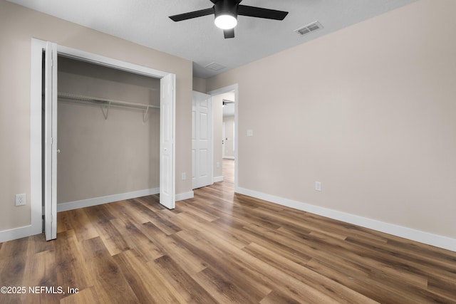 unfurnished bedroom featuring a closet, ceiling fan, visible vents, baseboards, and wood finished floors