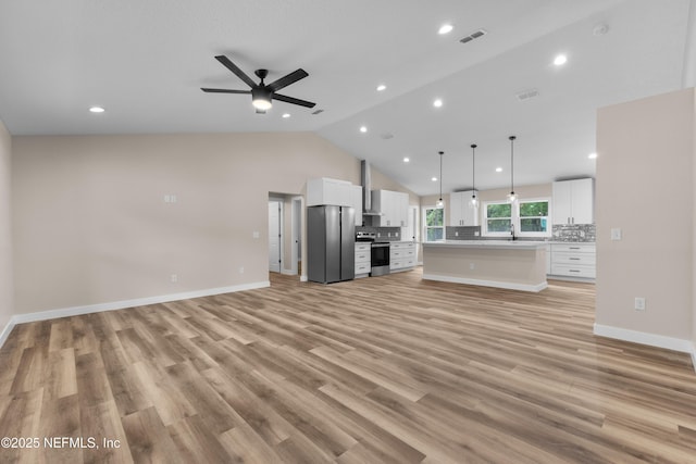 unfurnished living room with visible vents, light wood-style flooring, a ceiling fan, and lofted ceiling