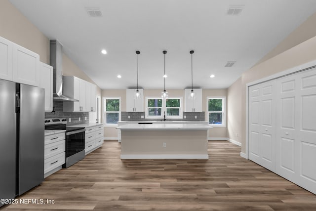 kitchen featuring appliances with stainless steel finishes, decorative backsplash, wall chimney range hood, and light countertops