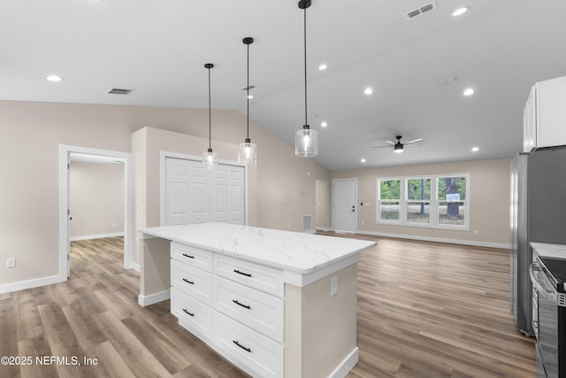 kitchen with stainless steel range with electric cooktop, a ceiling fan, visible vents, a kitchen island, and vaulted ceiling