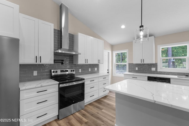 kitchen with wall chimney exhaust hood, appliances with stainless steel finishes, lofted ceiling, and white cabinetry