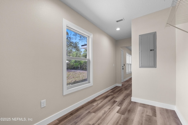 hallway with recessed lighting, wood finished floors, electric panel, baseboards, and visible vents