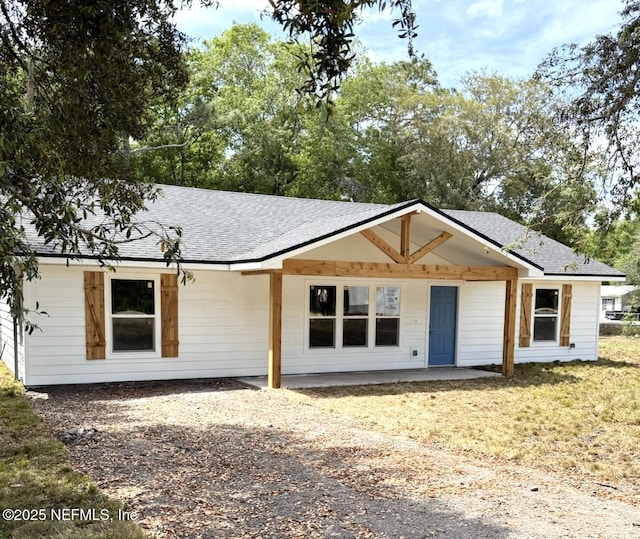 view of front facade with a patio and a shingled roof