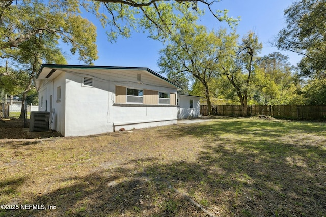 exterior space with central AC unit, a lawn, and fence