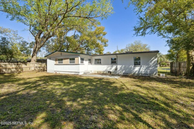 rear view of property featuring a patio area, fence, and a yard