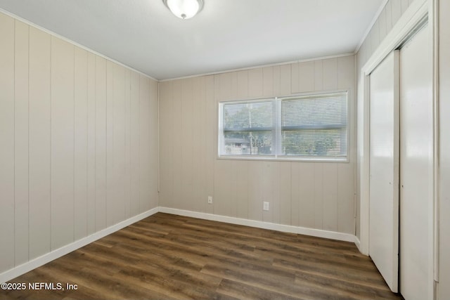 unfurnished bedroom featuring dark wood-type flooring, baseboards, and a closet