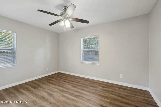 spare room featuring baseboards, wood finished floors, and ceiling fan
