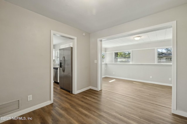 unfurnished room featuring dark wood-style flooring, a sink, baseboards, and visible vents