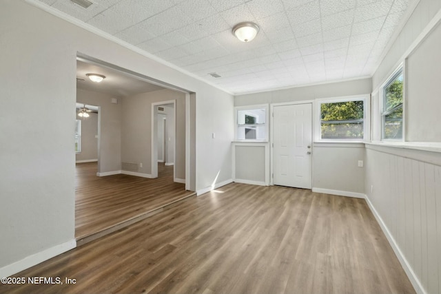 unfurnished room with crown molding, baseboards, and wood finished floors