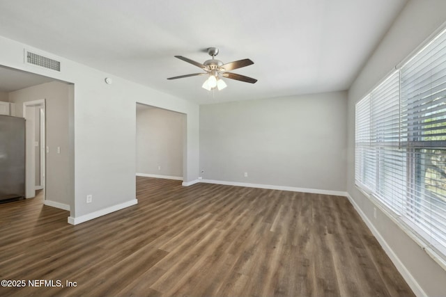empty room featuring baseboards, visible vents, wood finished floors, and a ceiling fan