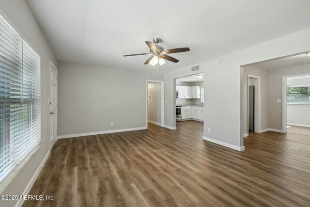 unfurnished living room with baseboards, dark wood-style flooring, visible vents, and a ceiling fan
