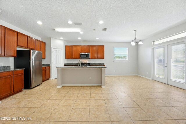 kitchen with an island with sink, a sink, stainless steel appliances, light tile patterned flooring, and a chandelier