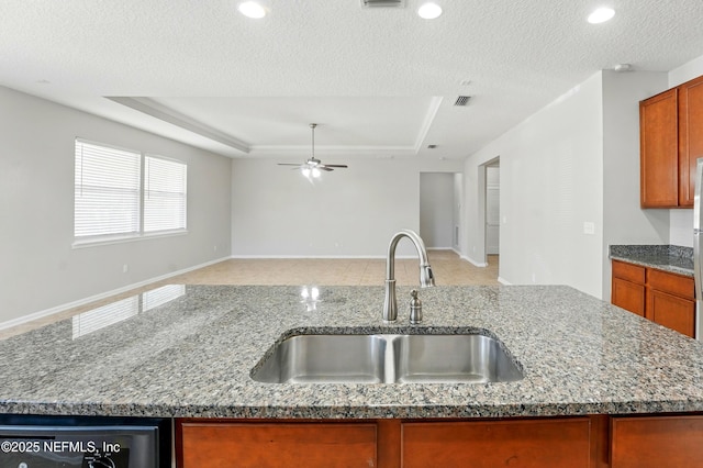 kitchen featuring open floor plan, a textured ceiling, a raised ceiling, and a sink
