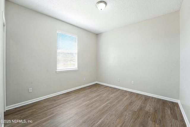 spare room featuring wood finished floors, baseboards, and a textured ceiling