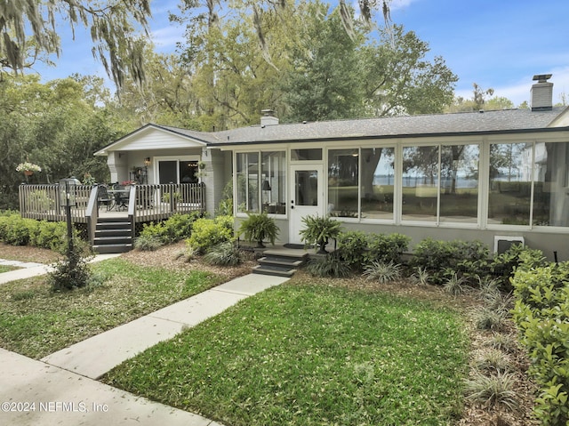 3079 Anderson Rd, Green Cove Springs, FL 32043 - view of front facade with a wooden deck, a front yard, a chimney, and a sunroom