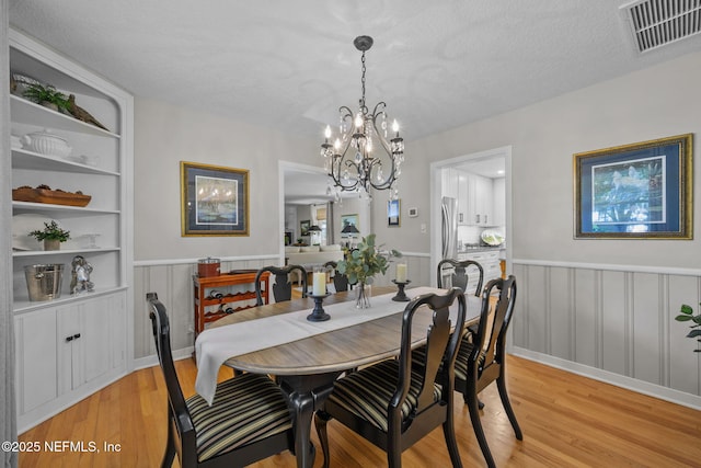 3079 Anderson Rd, Green Cove Springs, FL 32043 - dining area with built in features, visible vents, light wood-style floors, wainscoting, and a chandelier