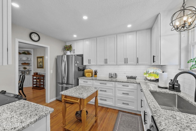3079 Anderson Rd, Green Cove Springs, FL 32043 - kitchen featuring light wood-style flooring, white cabinetry, freestanding refrigerator, and a sink