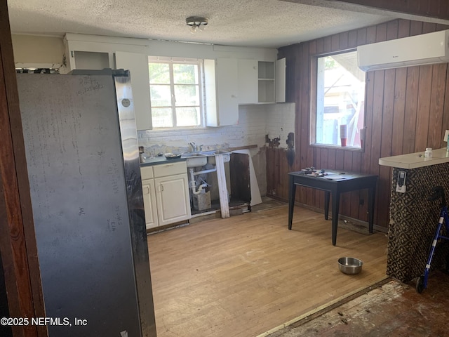 7823 Berry Ave, Jacksonville, FL 32211 - kitchen with light wood finished floors, a wall mounted air conditioner, freestanding refrigerator, a textured ceiling, and open shelves