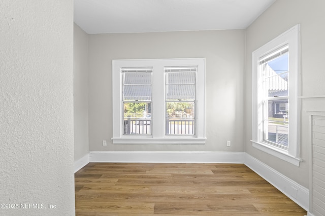 spare room featuring baseboards and light wood-style floors