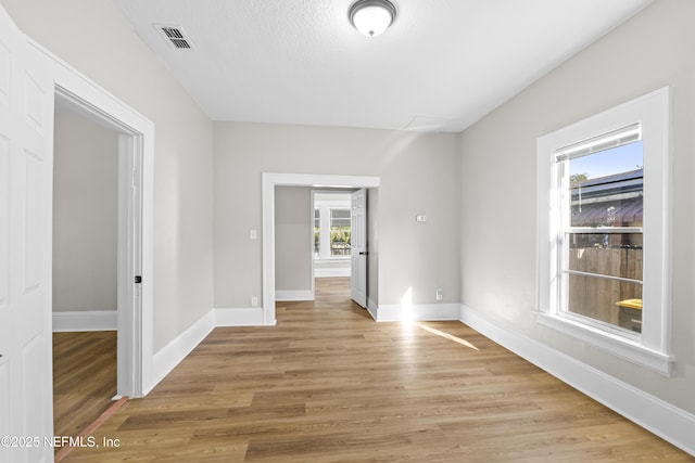 spare room featuring visible vents, baseboards, and light wood finished floors
