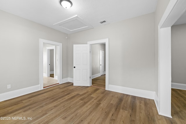 interior space with visible vents, baseboards, attic access, and wood finished floors