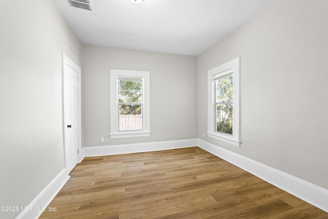 unfurnished room featuring light wood-style flooring, baseboards, and visible vents