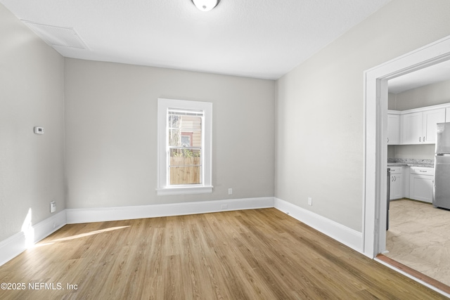 spare room featuring light wood-style floors and baseboards