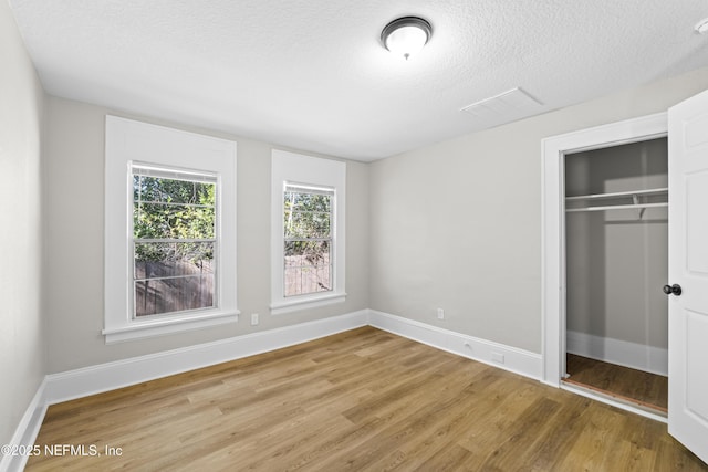 unfurnished bedroom with visible vents, wood finished floors, and baseboards
